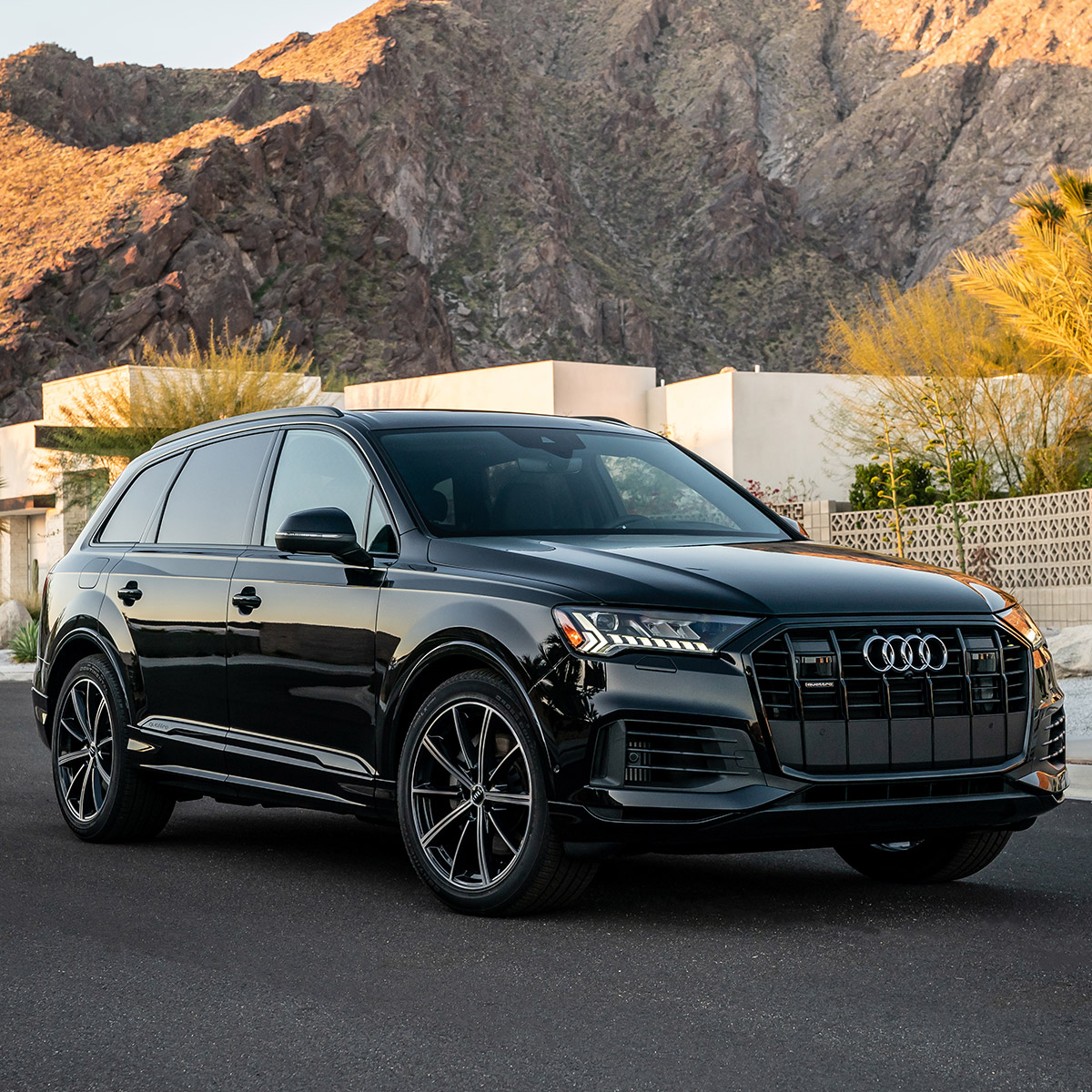 side profile of audi Q7 suv in black color parked on pavement in front of a white house
