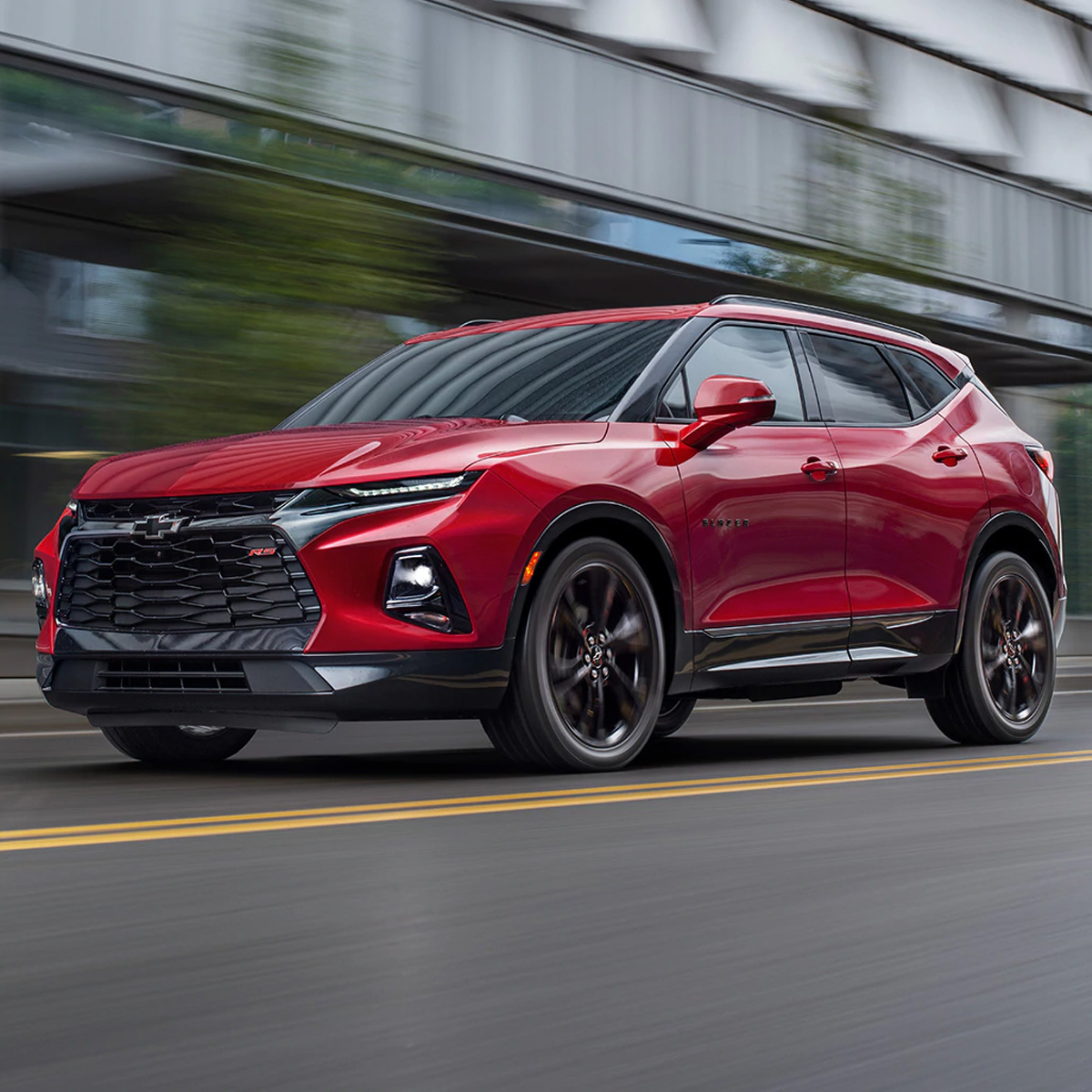 side profile of chevrolet blazer suv in red color parked in driving in front of a commercial building