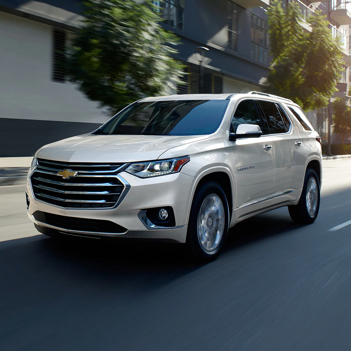 side profile of chevrolet traverse suv in white color driving through the city streets
