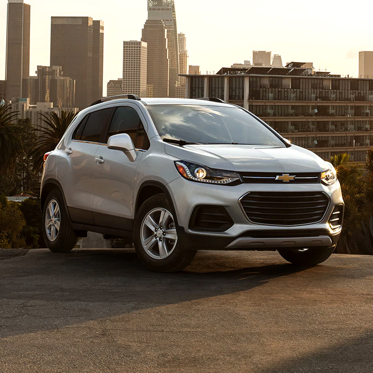 side profile of chevrolet trax crossover in white color driving throught the city streets