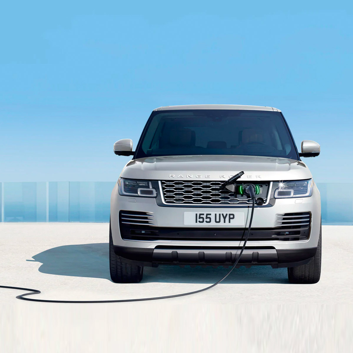 frontal profile of land rover range rover hybrid suv getting charged from the frontal grill